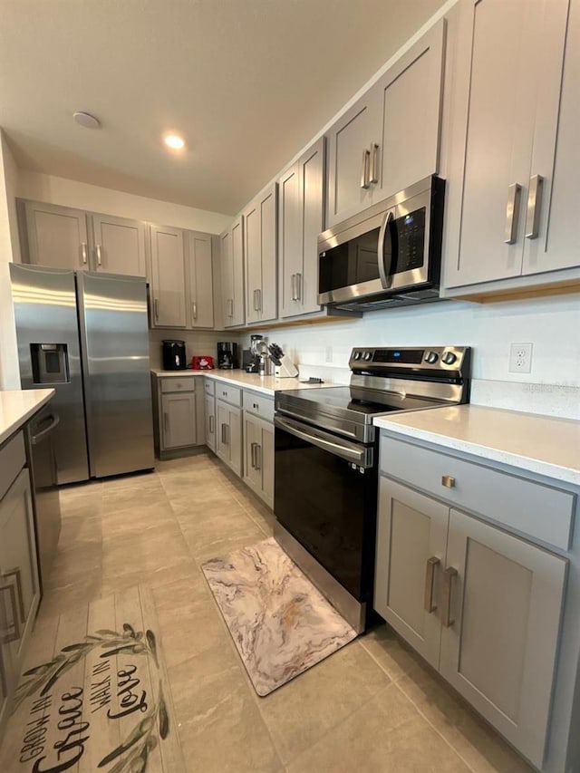 kitchen with appliances with stainless steel finishes, gray cabinets, and light tile patterned floors