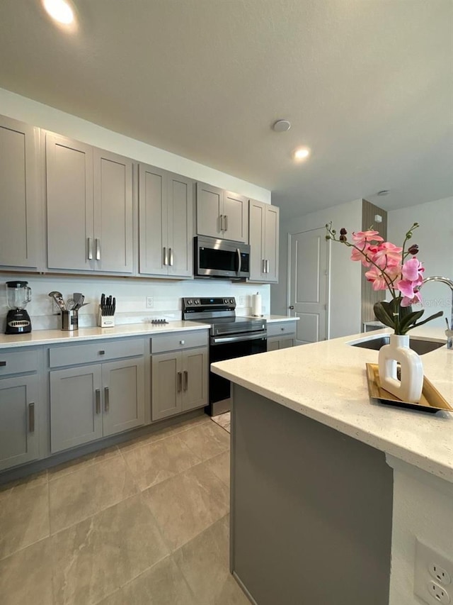 718 Longboat Dr, Davenport, FL 33896 - kitchen with stainless steel appliances, gray cabinets, light stone countertops, and recessed lighting