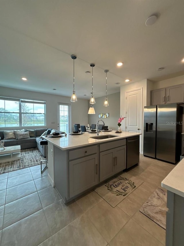 kitchen featuring sink, pendant lighting, stainless steel refrigerator with ice dispenser, a center island with sink, and dishwasher