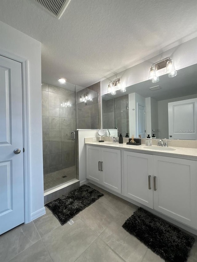 bathroom featuring vanity, a textured ceiling, and a shower with door