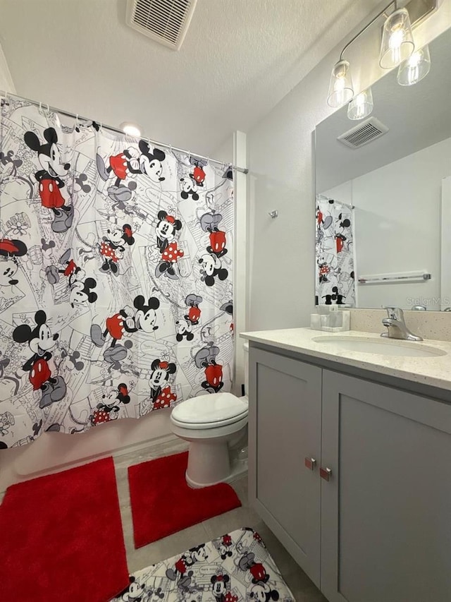 bathroom featuring tile patterned flooring, toilet, a shower with curtain, vanity, and a textured ceiling