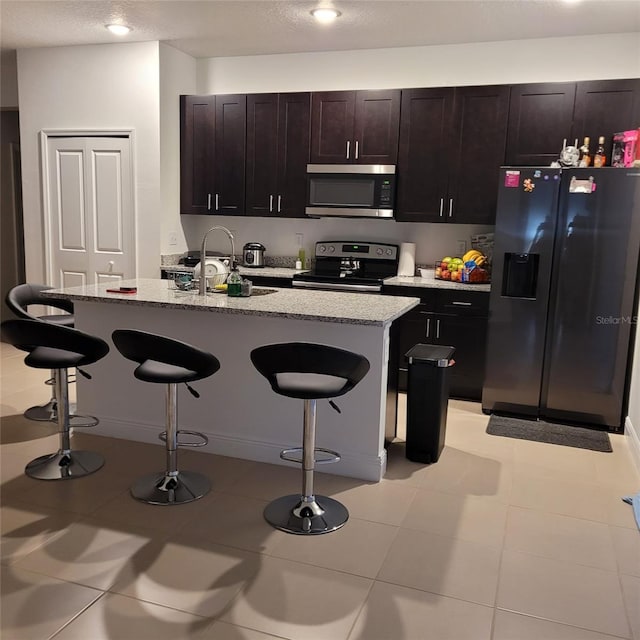 kitchen featuring light stone counters, a breakfast bar area, stainless steel appliances, and sink