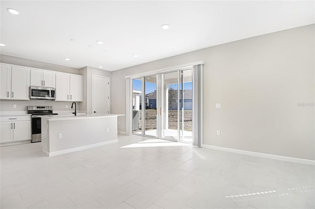 kitchen featuring white cabinets, appliances with stainless steel finishes, a center island with sink, and light tile patterned floors