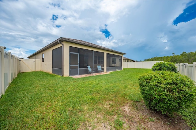 back of house featuring a sunroom and a lawn