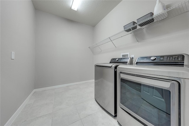 laundry area with light tile patterned floors, a textured ceiling, and washer and clothes dryer