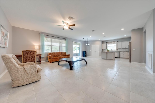 tiled living room featuring ceiling fan with notable chandelier