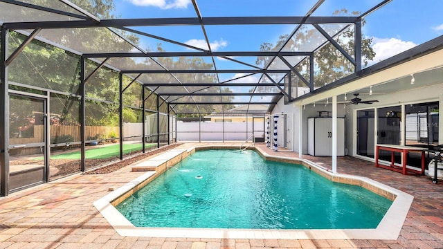 view of swimming pool with glass enclosure, a patio, ceiling fan, and pool water feature