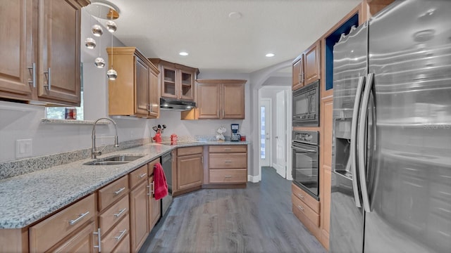 kitchen featuring black appliances, sink, hardwood / wood-style floors, and light stone countertops