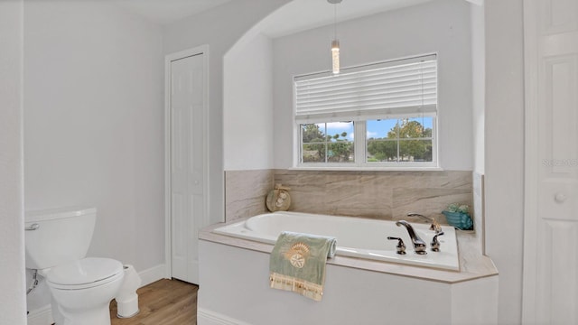 bathroom with toilet, hardwood / wood-style floors, and a tub