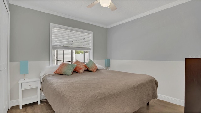 bedroom with ornamental molding, wood-type flooring, ceiling fan, and a closet