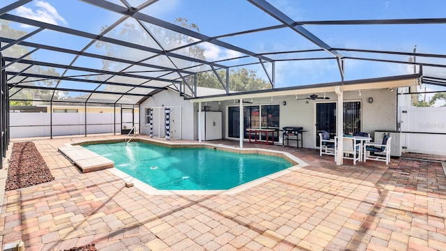 view of swimming pool with ceiling fan, a patio area, and glass enclosure