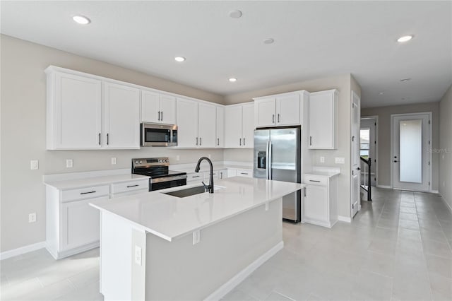 kitchen with sink, light tile patterned flooring, a kitchen island with sink, white cabinets, and appliances with stainless steel finishes