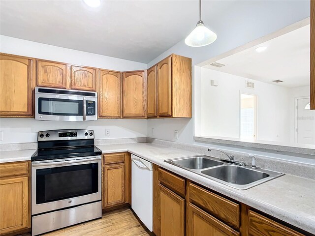 kitchen featuring light hardwood / wood-style flooring, decorative light fixtures, stainless steel appliances, and sink