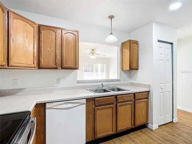 kitchen with white dishwasher, light wood-type flooring, sink, ceiling fan, and pendant lighting