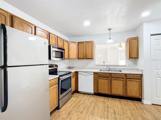 kitchen with light hardwood / wood-style floors, hanging light fixtures, stainless steel appliances, sink, and ceiling fan