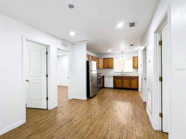 kitchen featuring pendant lighting, light hardwood / wood-style flooring, stainless steel appliances, and sink