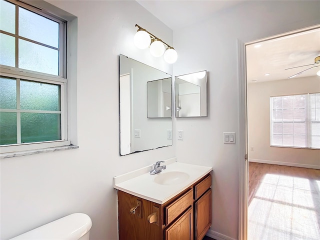 bathroom featuring vanity, toilet, hardwood / wood-style floors, and ceiling fan