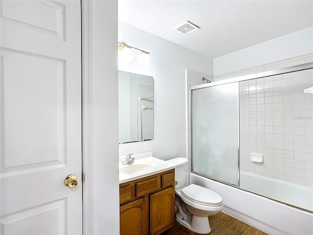 full bathroom featuring shower / bath combination with glass door, vanity, toilet, and hardwood / wood-style floors