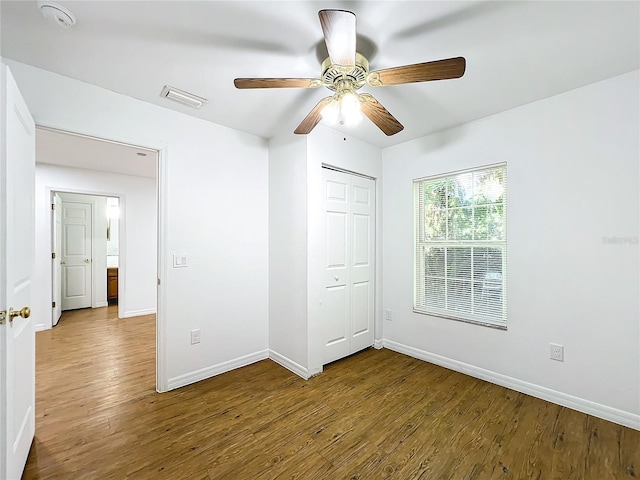 unfurnished bedroom featuring ceiling fan, a closet, and hardwood / wood-style flooring