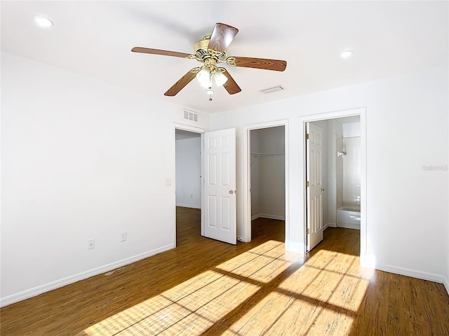 unfurnished bedroom featuring ceiling fan, light wood-type flooring, a spacious closet, and ensuite bathroom