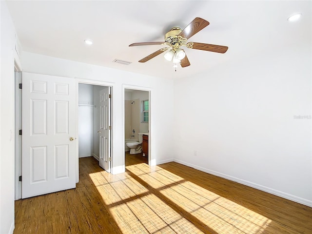 unfurnished bedroom featuring ensuite bathroom, light wood-type flooring, a closet, a spacious closet, and ceiling fan