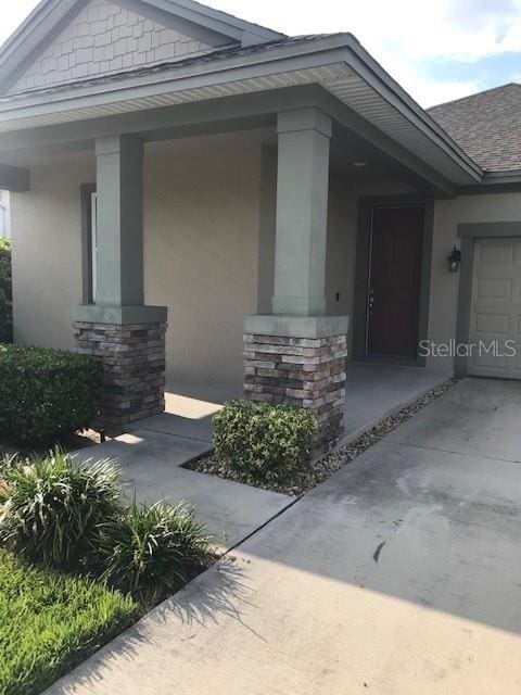 entrance to property featuring covered porch and stucco siding