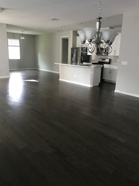 interior space featuring dark wood-style floors, baseboards, an inviting chandelier, and a sink