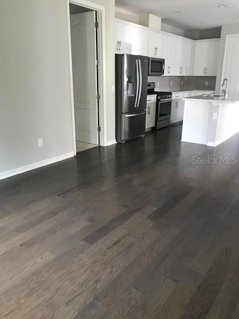 kitchen featuring dark wood-type flooring, stainless steel appliances, and white cabinetry