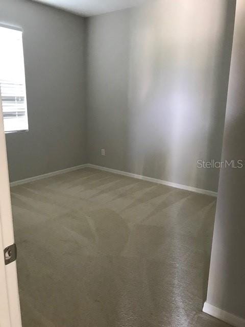 empty room featuring carpet and baseboards