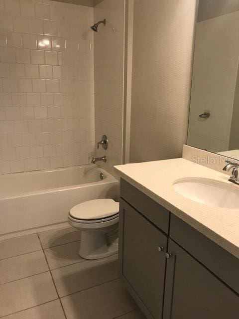 full bathroom with tiled shower / bath, vanity, toilet, and tile patterned floors