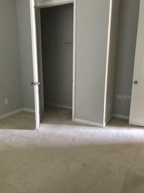 unfurnished bedroom with a closet and light carpet