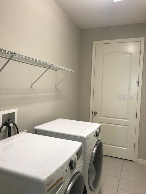 laundry room with light tile patterned floors, laundry area, washer and dryer, and baseboards