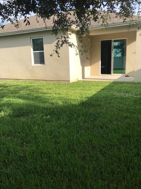 rear view of property with a patio, a lawn, and stucco siding