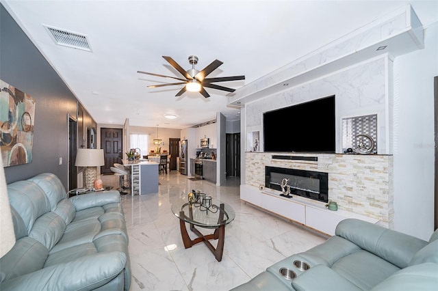 living room featuring ceiling fan and a fireplace