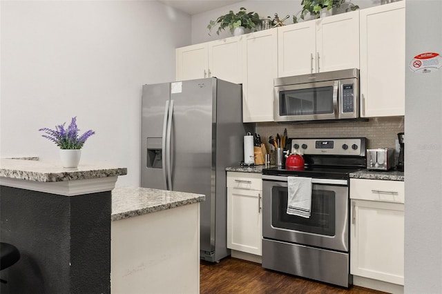 kitchen with dark wood-type flooring, light stone counters, stainless steel appliances, and white cabinetry