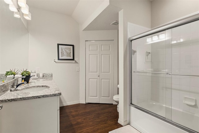 full bathroom featuring toilet, combined bath / shower with glass door, vanity, vaulted ceiling, and hardwood / wood-style flooring