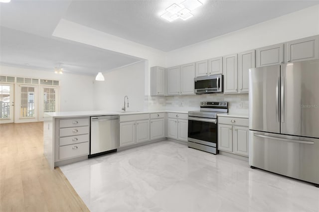 kitchen featuring tasteful backsplash, stainless steel appliances, kitchen peninsula, sink, and ceiling fan