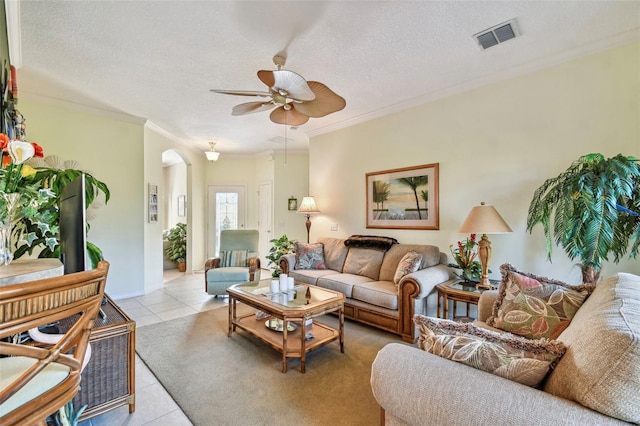 living room with ceiling fan, light tile patterned floors, ornamental molding, and a textured ceiling