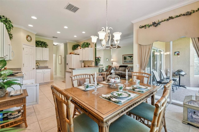 dining room with sink, light tile patterned floors, an inviting chandelier, and ornamental molding