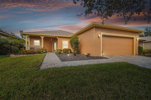 ranch-style house featuring a garage, covered porch, and a lawn