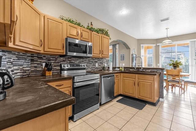 kitchen with sink, hanging light fixtures, stainless steel appliances, kitchen peninsula, and a textured ceiling