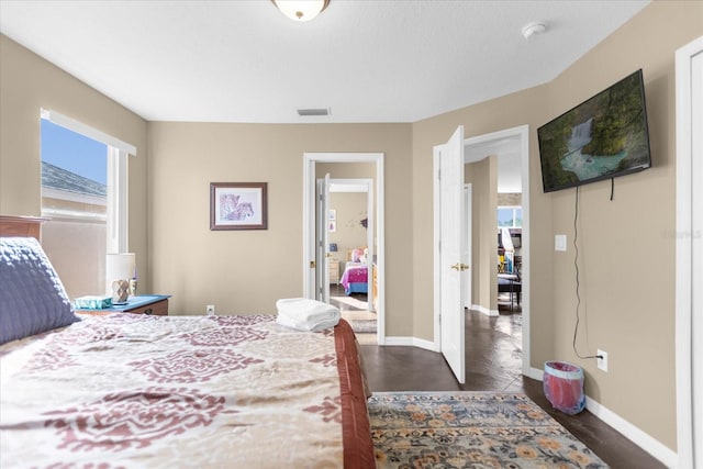 bedroom with multiple windows and dark wood-type flooring