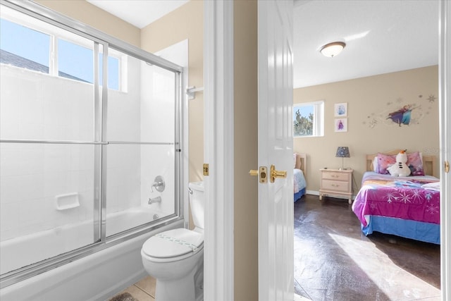 bathroom featuring toilet and bath / shower combo with glass door