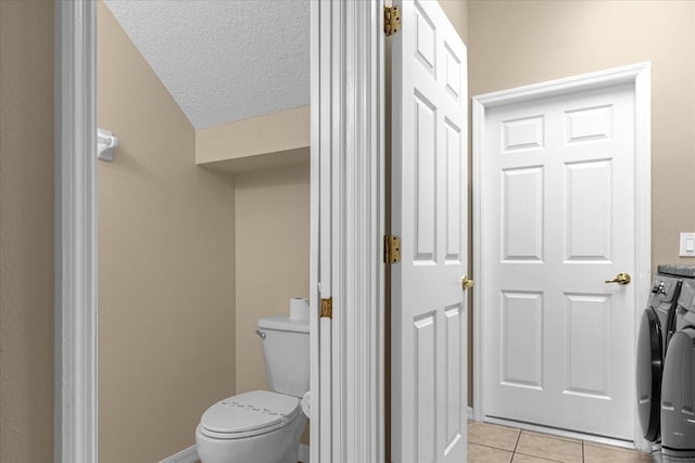 bathroom featuring tile patterned floors, a textured ceiling, toilet, and washing machine and clothes dryer