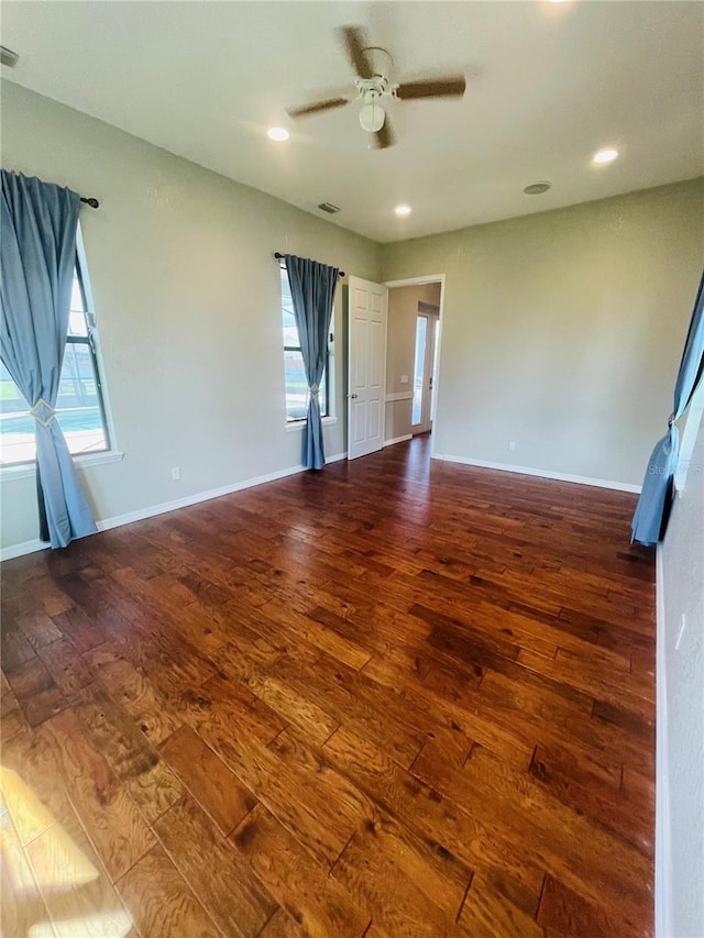 empty room with a wealth of natural light, ceiling fan, and dark hardwood / wood-style floors