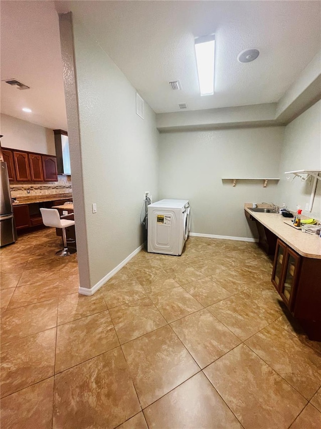 clothes washing area with a textured ceiling and light tile patterned floors