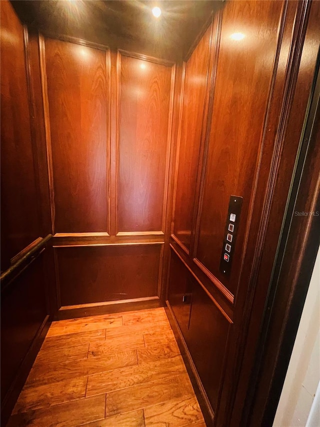 interior details featuring elevator and hardwood / wood-style flooring