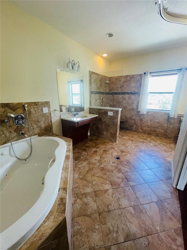 bathroom with a wealth of natural light, vanity, separate shower and tub, and a textured ceiling