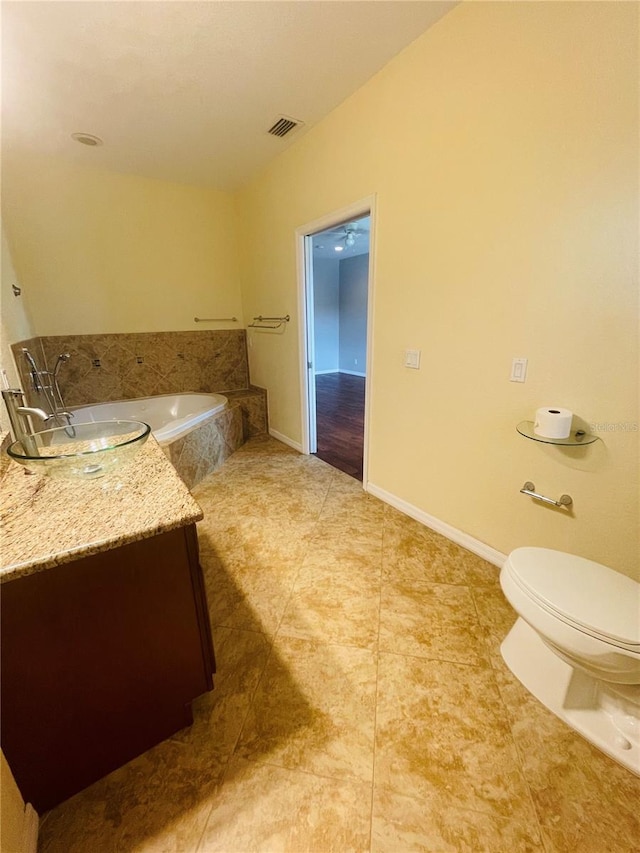 bathroom featuring vanity, tiled tub, tile patterned floors, and toilet