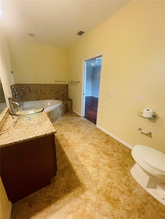 bathroom with vanity, toilet, tile patterned floors, and tiled bath